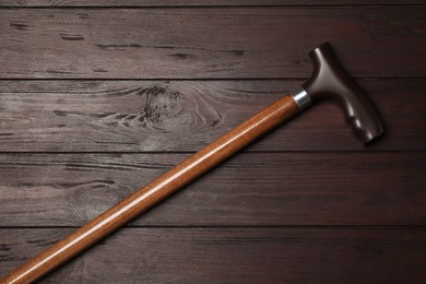 Photo of Elegant walking cane on wooden table, top view