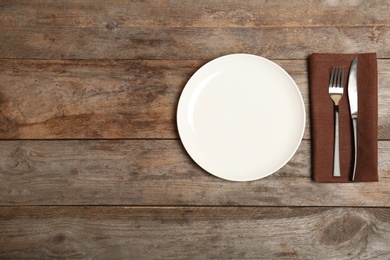 Photo of Empty dishware and cutlery on wooden background, top view. Table setting