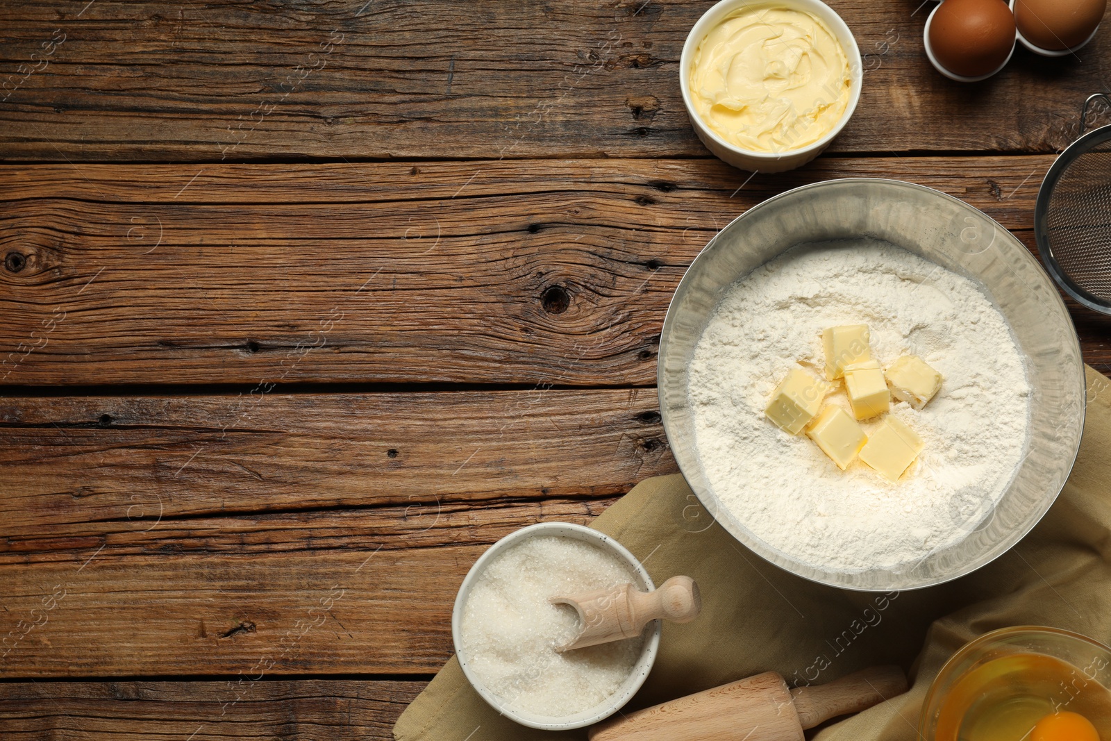 Photo of Flat lay composition with fresh butter and flour in bowl among other products on wooden table. Space for text