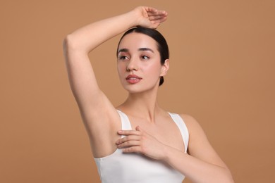 Beautiful woman showing armpit with smooth clean skin on beige background