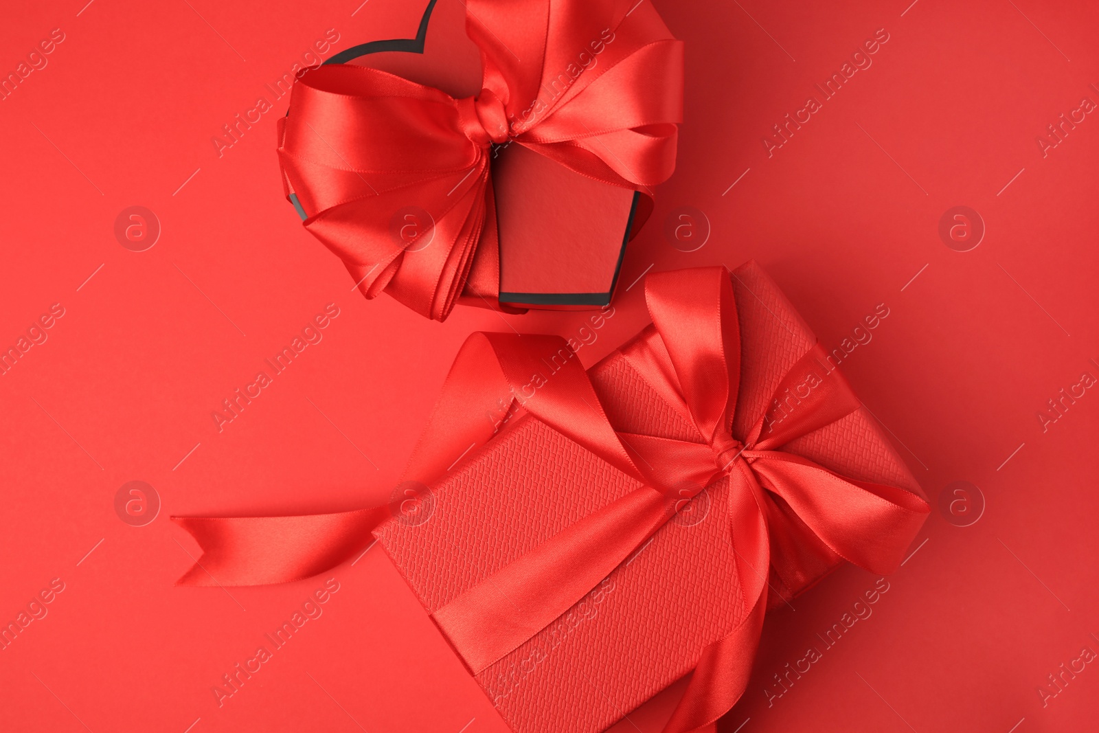 Photo of Beautiful gift boxes with bows on red background, flat lay