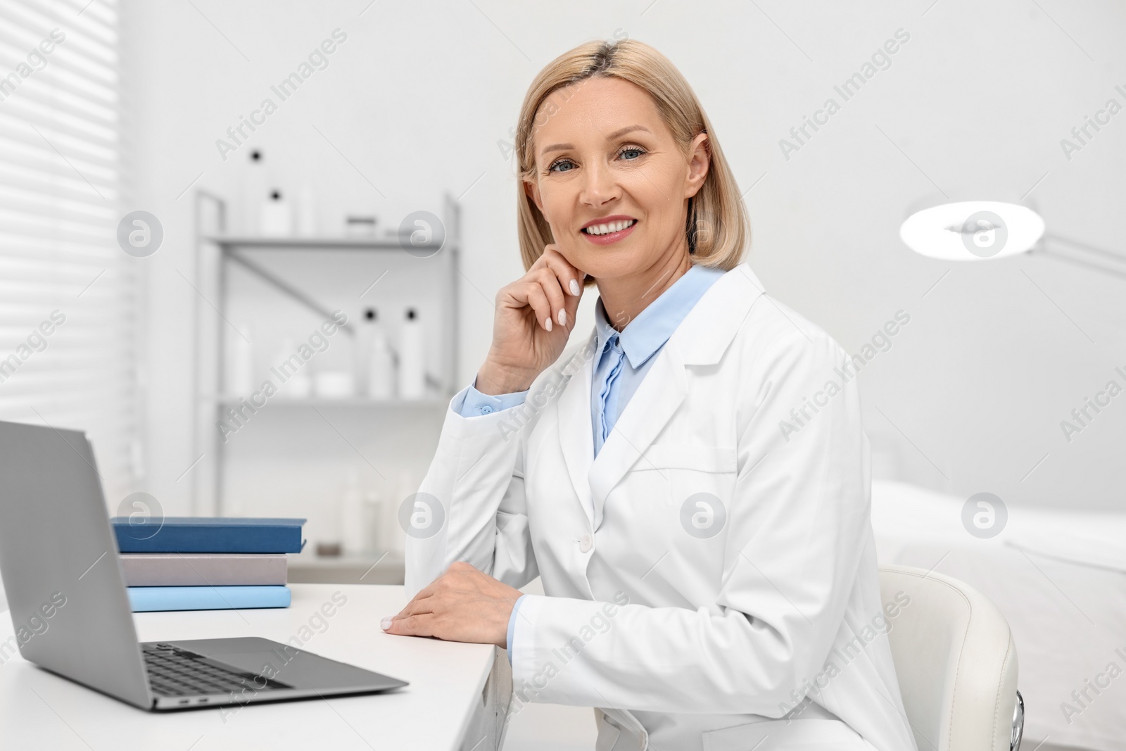 Photo of Portrait of happy dermatologist at white table in clinic