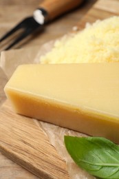 Delicious parmesan cheese and basil on wooden table, closeup