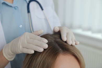 Photo of Young woman visiting trichologist in clinic, closeup