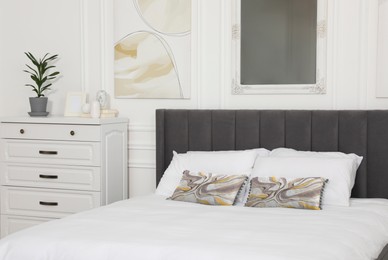 Image of Soft pillows with stylish abstract prints on bed indoors