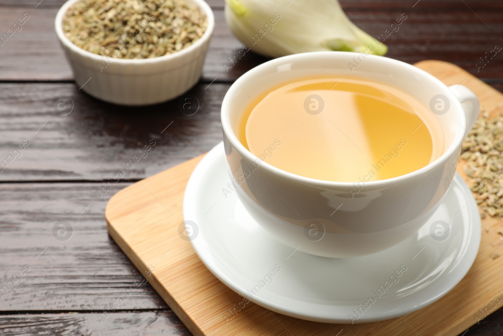 Photo of Fennel tea in cup and seeds on wooden table, closeup