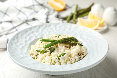 Photo of Delicious risotto with asparagus on white wooden table, closeup