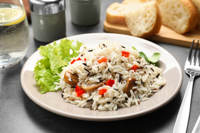Delicious rice pilaf with mushrooms on grey table