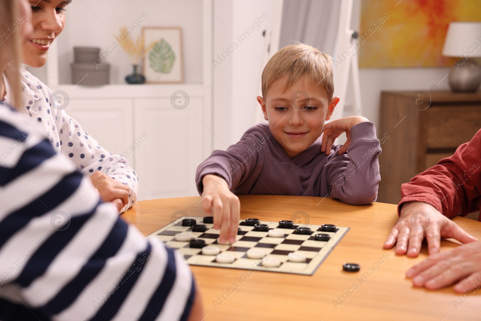 Photo of Family playing checkers at wooden table in room