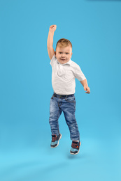 Photo of Cute little boy jumping on blue background