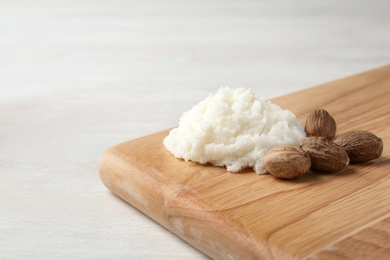 Photo of Shea butter and nuts on wooden board. Space for text