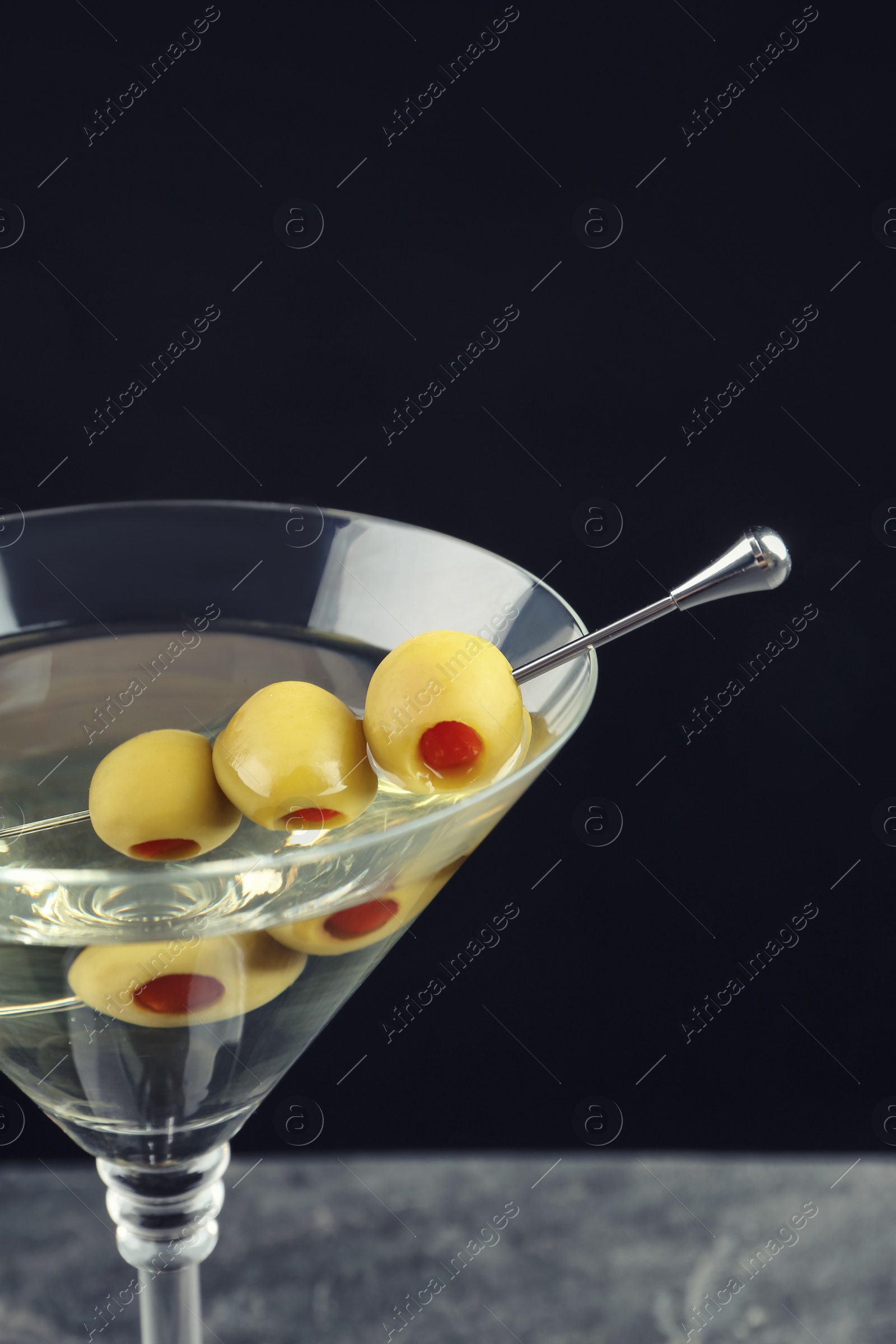 Photo of Martini cocktail with olives on table against dark background, closeup