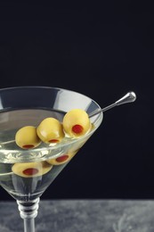 Photo of Martini cocktail with olives on table against dark background, closeup