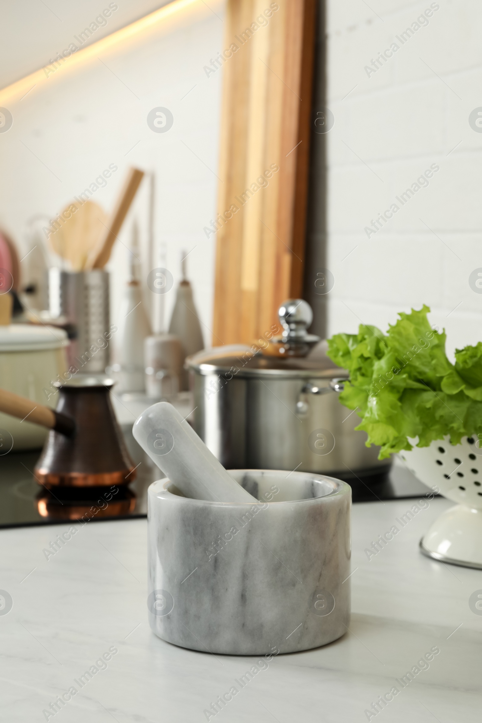 Photo of Marble mortar with pestle on kitchen counter. Cooking utensils