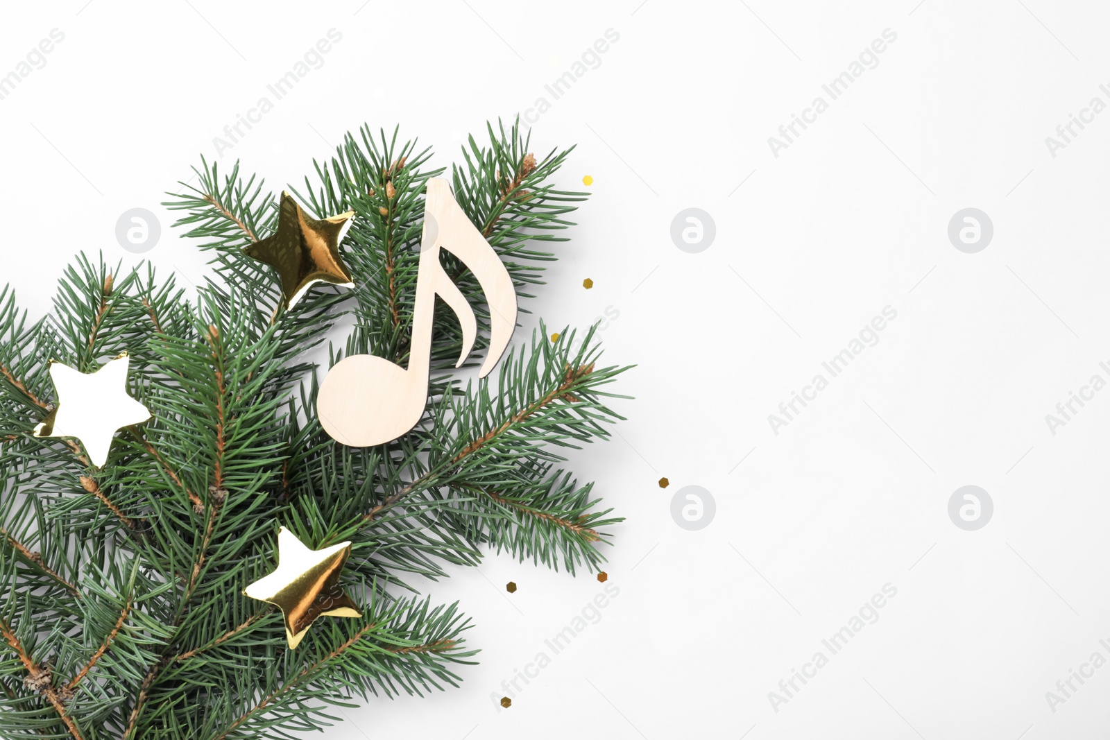 Photo of Fir tree branch with decorative golden stars and wooden music note on white background, top view. Christmas celebration