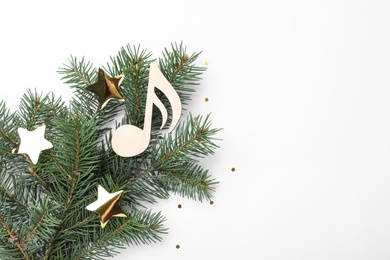 Fir tree branch with decorative golden stars and wooden music note on white background, top view. Christmas celebration