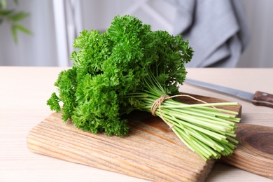 Photo of Wooden board with fresh green parsley on table