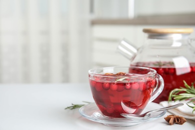 Photo of Tasty hot cranberry tea in glass cup on white table. Space for text