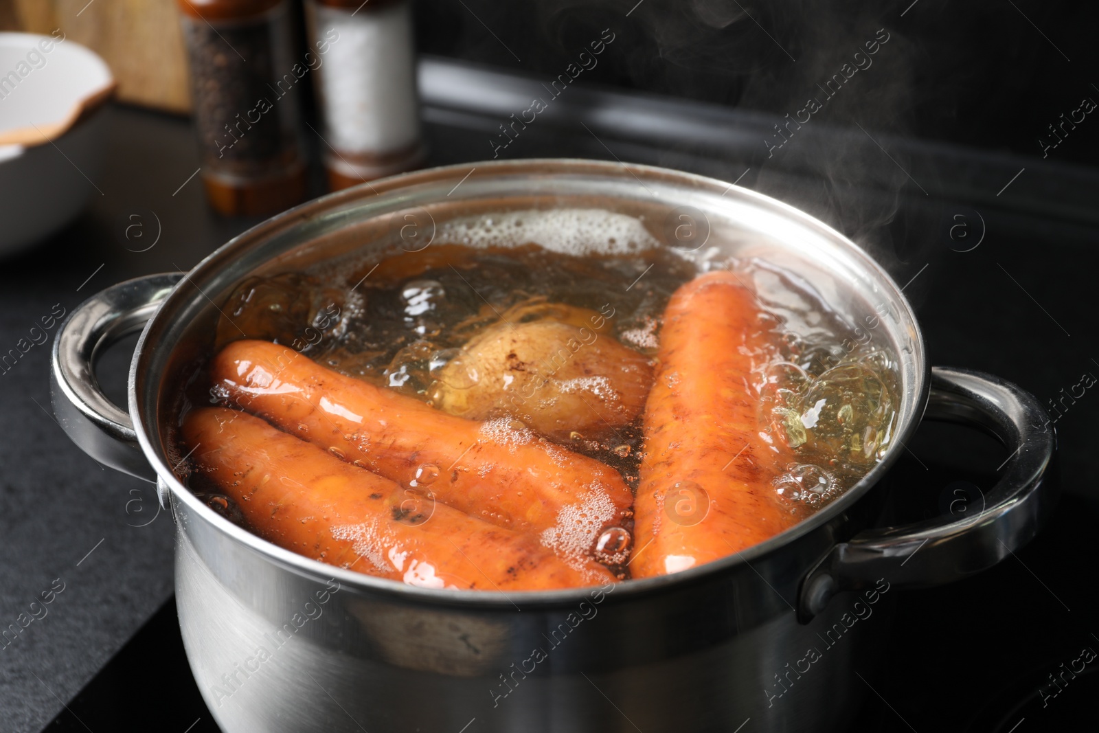 Photo of Boiling carrot and potatoes in pot on electric stove, closeup. Cooking vinaigrette salad