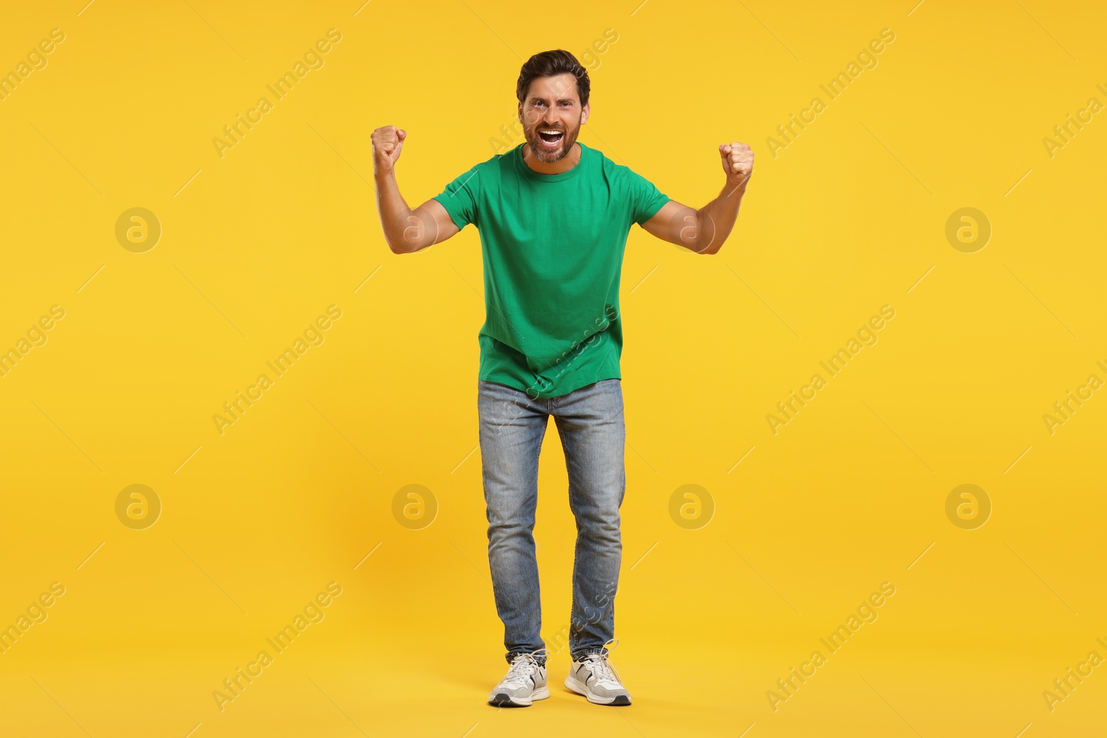 Photo of Emotional sports fan celebrating on yellow background