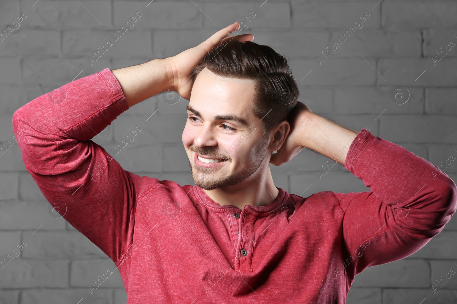 Photo of Portrait of young man with beautiful hair on brick wall background