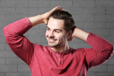 Photo of Portrait of young man with beautiful hair on brick wall background