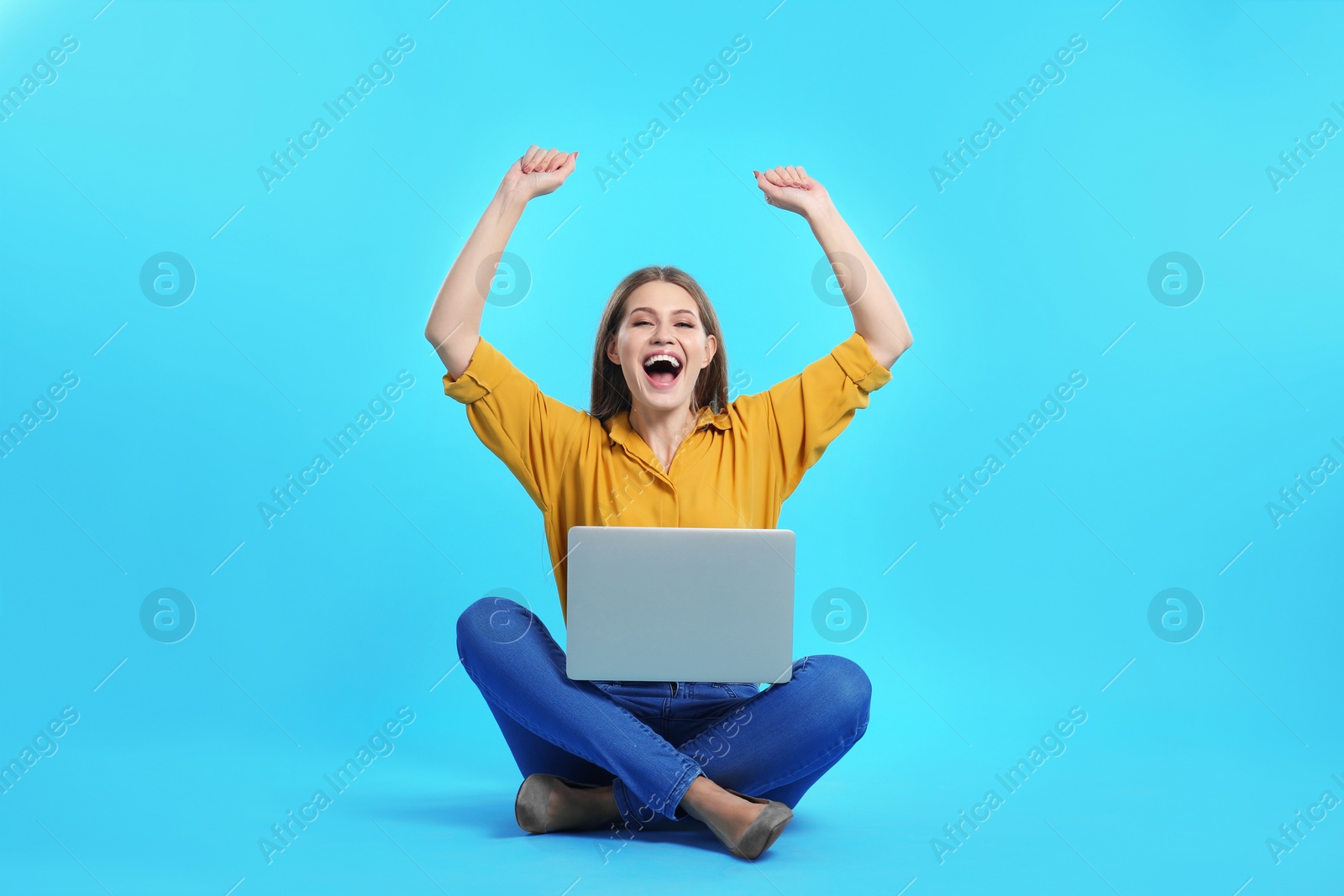 Photo of Emotional young woman with laptop celebrating victory on color background