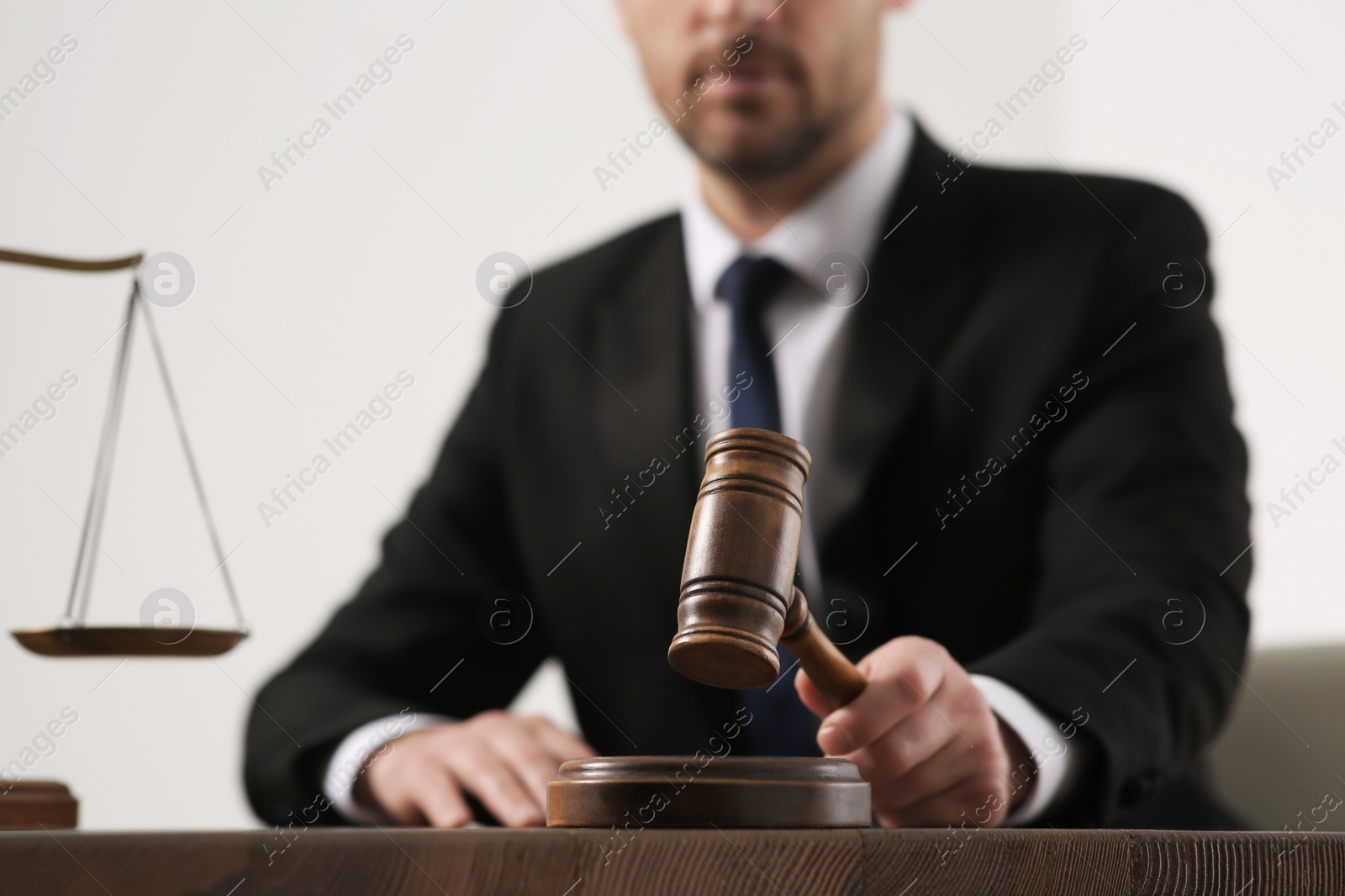 Photo of Law and justice. Closeup of judge with gavel at wooden table, selective focus