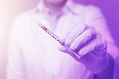 Image of Doctor holding syringe, selective focus. Color toned