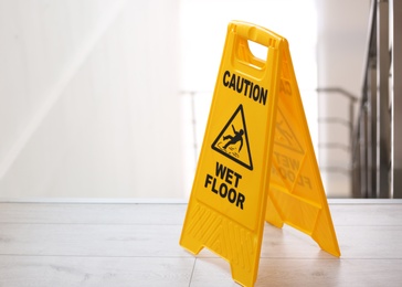 Safety sign with phrase Caution wet floor near stairs