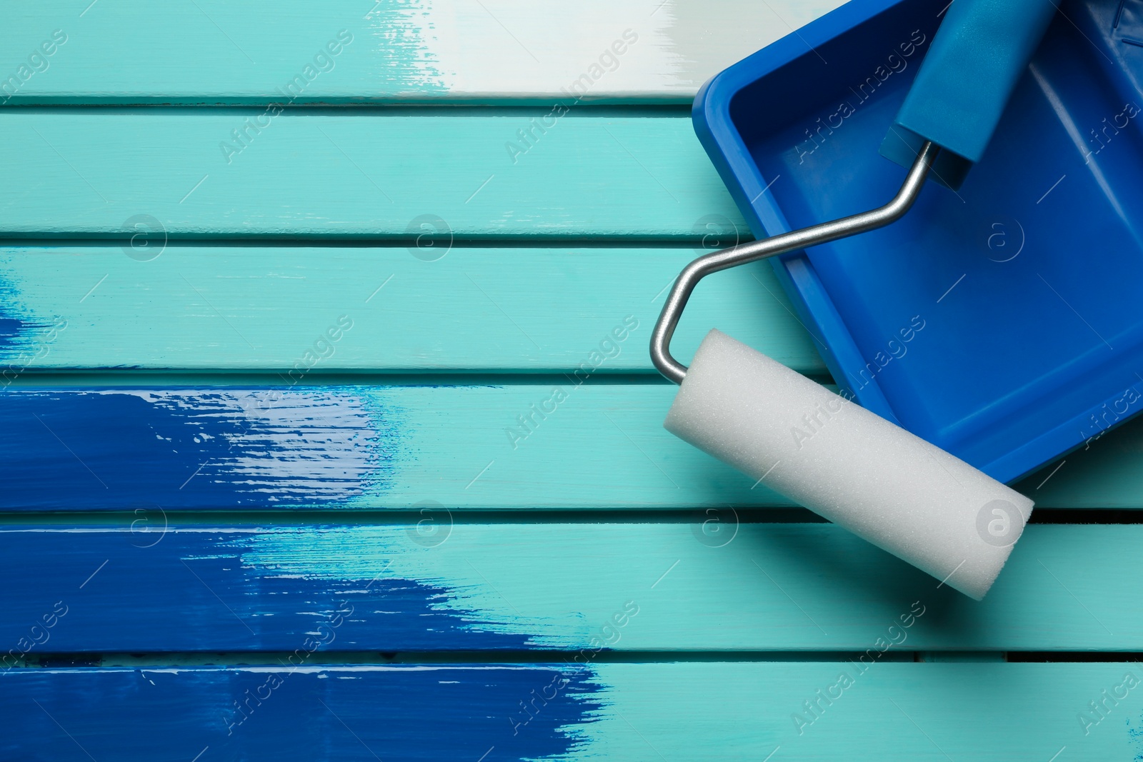 Photo of Paint stroke, roller and tray on blue wooden background, top view. Space for text