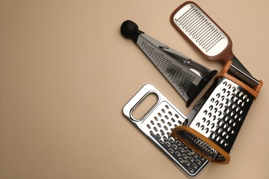 Photo of Different modern graters on beige background, flat lay. Space for text