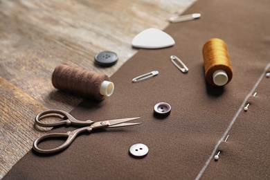 Set of tailoring accessories and fabric on wooden background