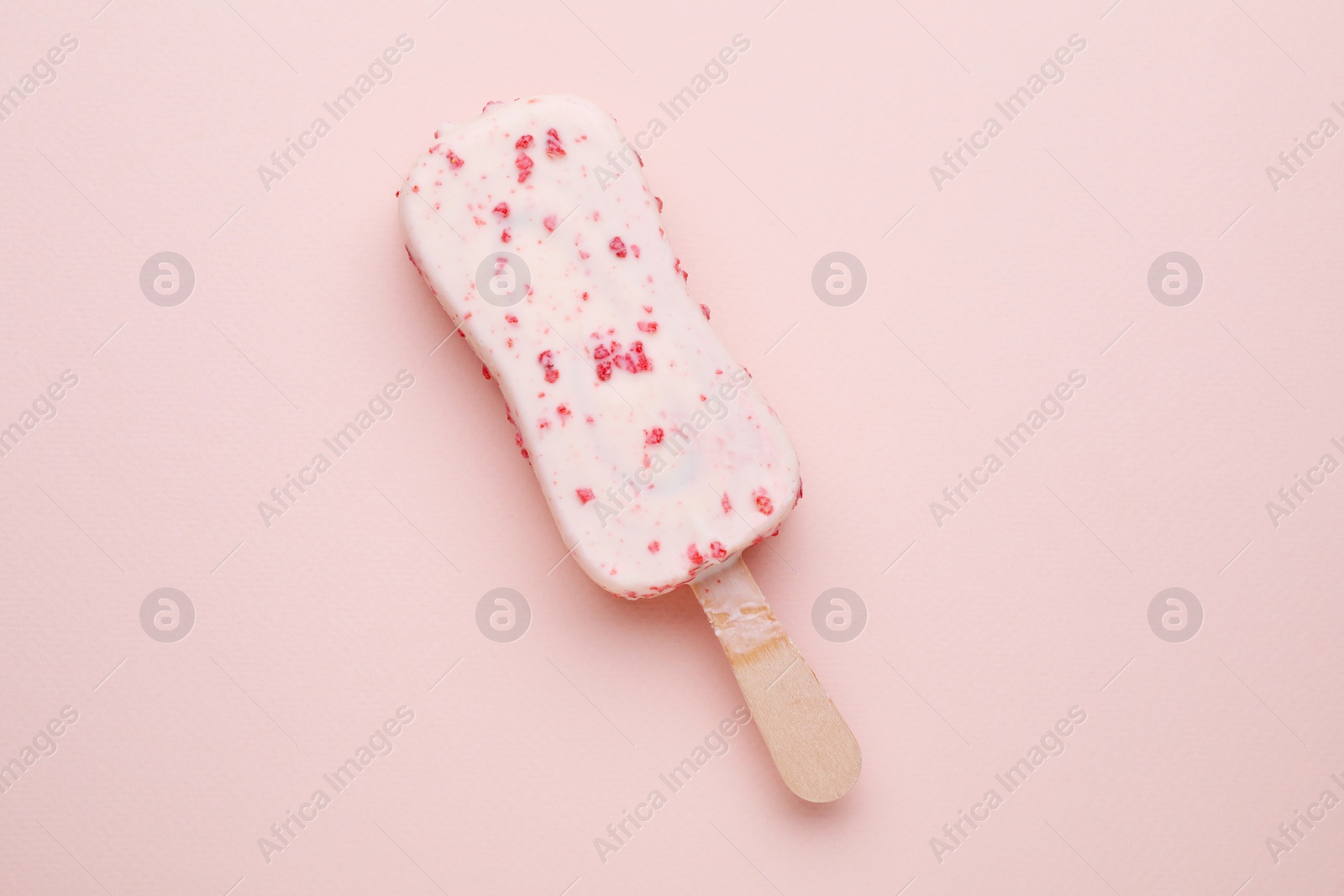 Photo of Delicious glazed ice cream bar on pale pink background, top view