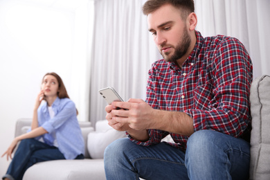 Photo of Couple addicted to smartphones at home. Relationship problems