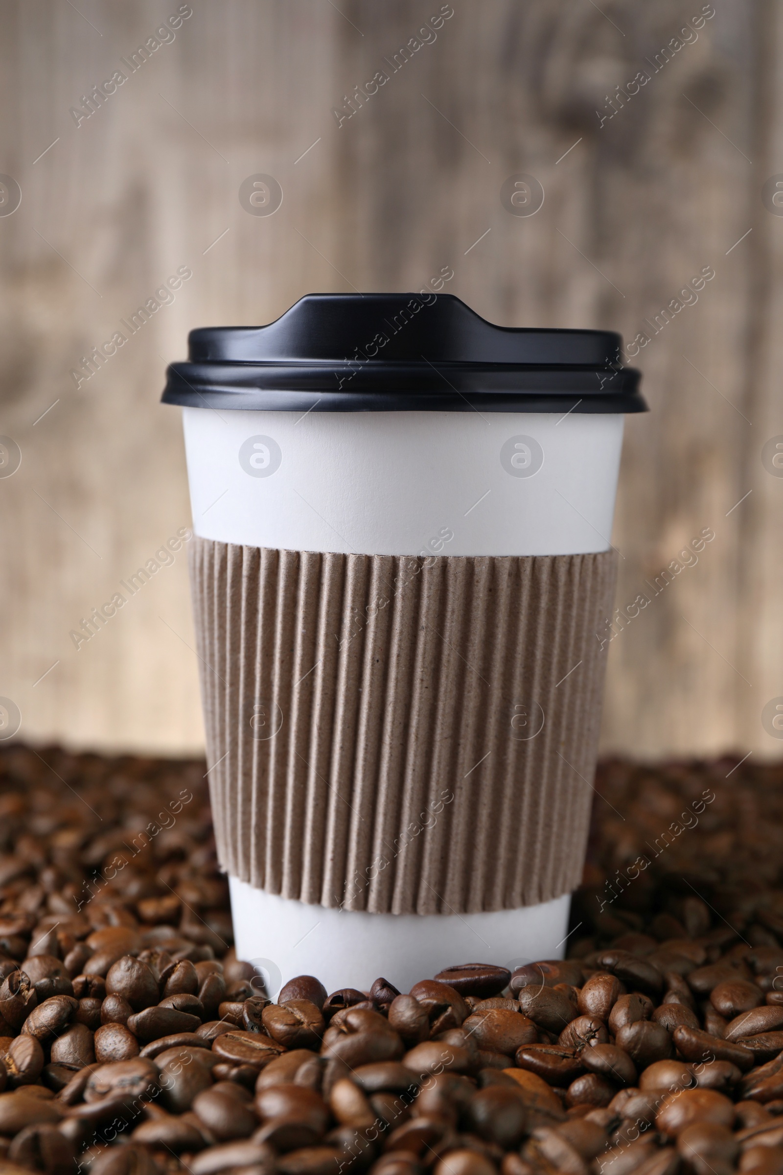 Photo of Coffee to go. Paper cup on roasted beans, closeup