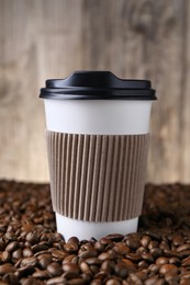 Coffee to go. Paper cup on roasted beans, closeup