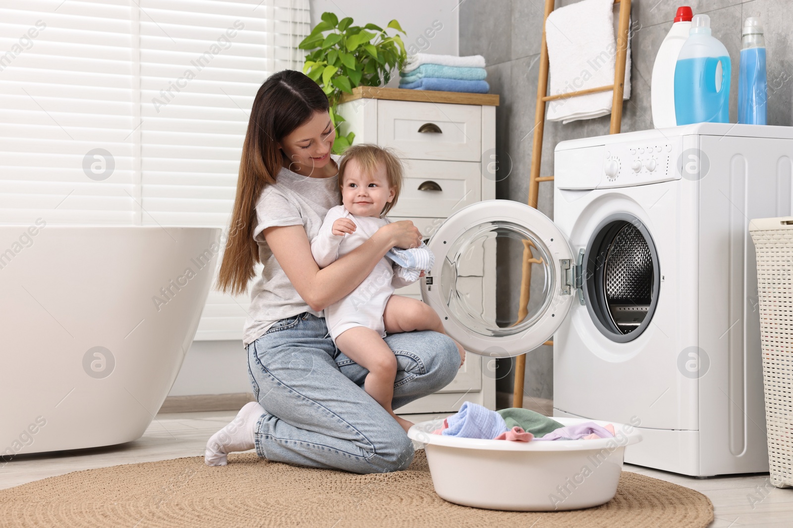 Photo of Mother with her daughter washing baby clothes in bathroom