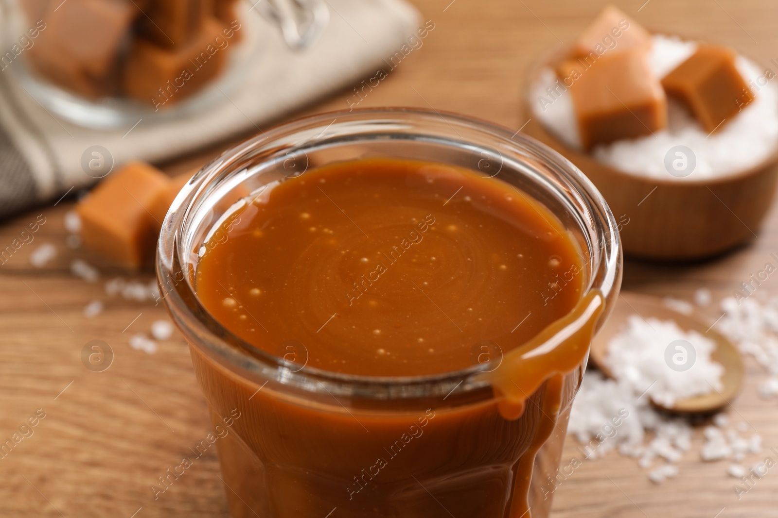 Photo of Tasty salted caramel in glass on table, closeup