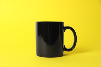Photo of One black ceramic mug on yellow background