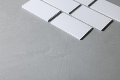 Blank business cards on light grey textured table, closeup. Mockup for design