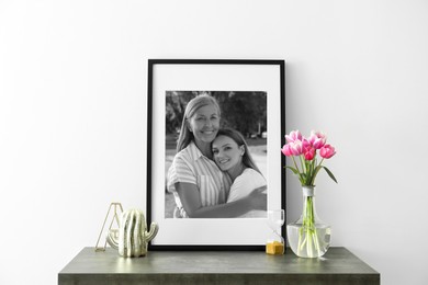 Image of Black and white family portrait of mother and daughter in photo frame on table near white wall