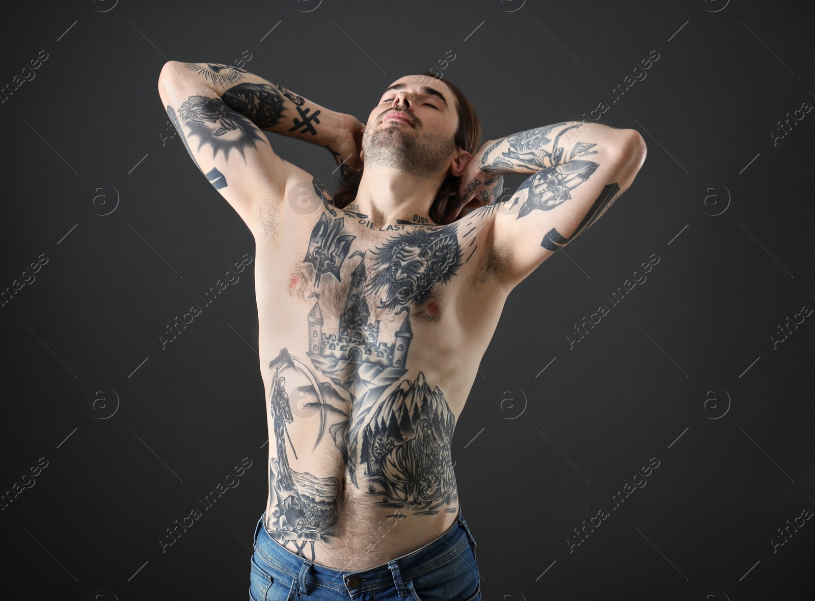 Photo of Young man with tattoos on body against black background