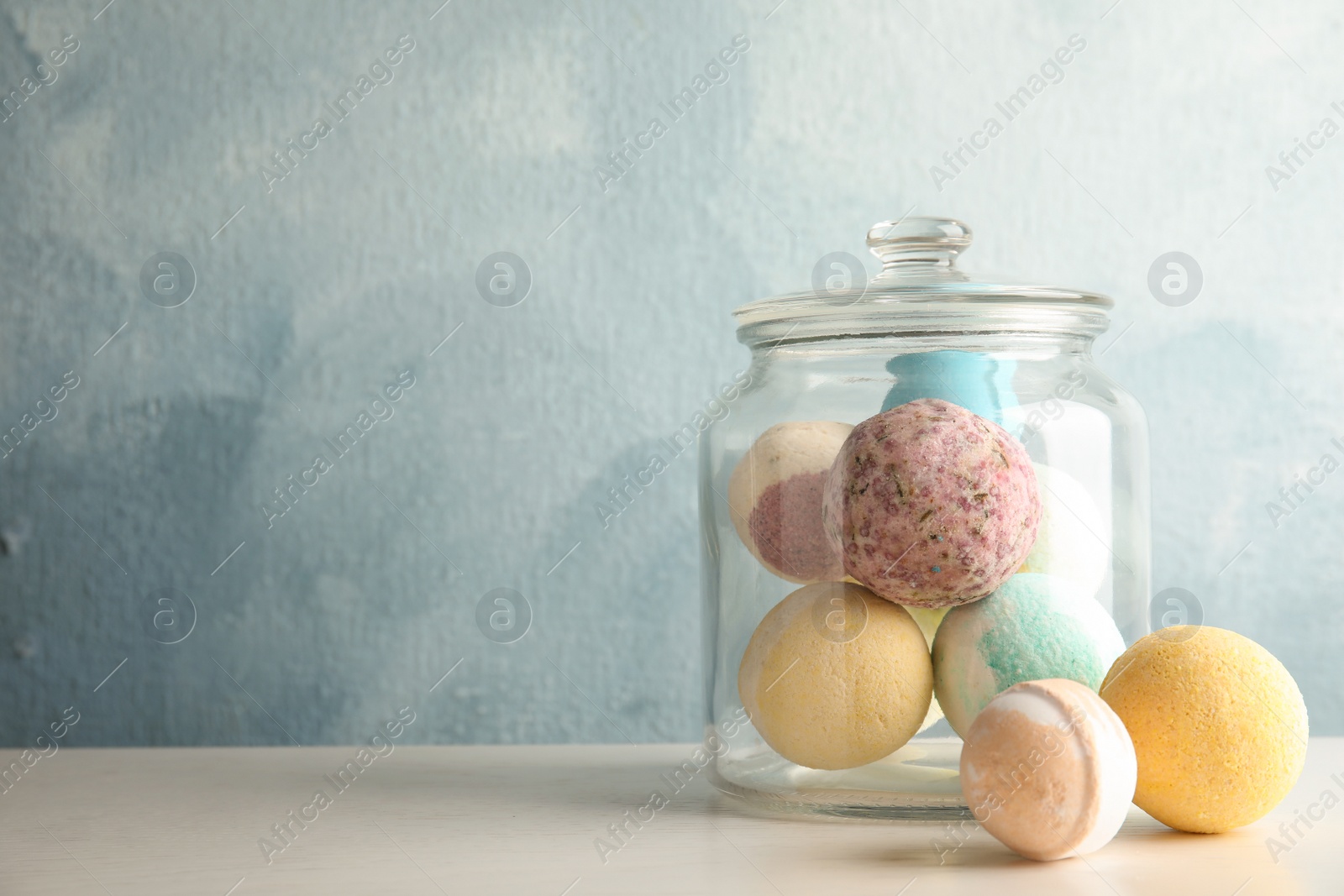 Photo of Jar with colorful bath bombs on table. Space for text