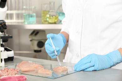 Photo of Scientist injecting liquid into meat sample in laboratory. Food quality control