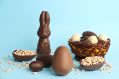 Photo of Sweet chocolate eggs and bunny on light blue background