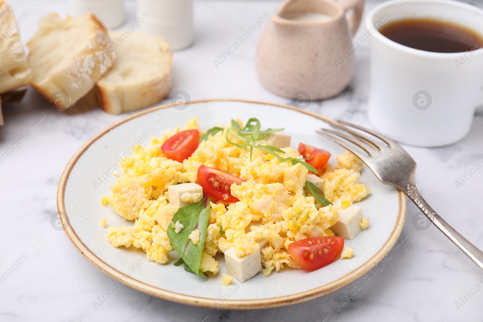 Photo of Plate with delicious scrambled eggs, tofu and tomatoes on white marble table