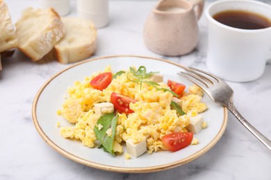 Plate with delicious scrambled eggs, tofu and tomatoes on white marble table