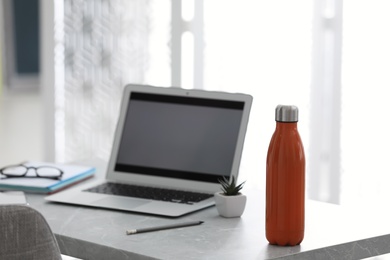 Thermo bottle on table in modern office