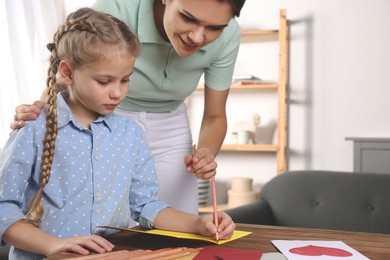 Cute little girl with her mother making beautiful greeting card at home